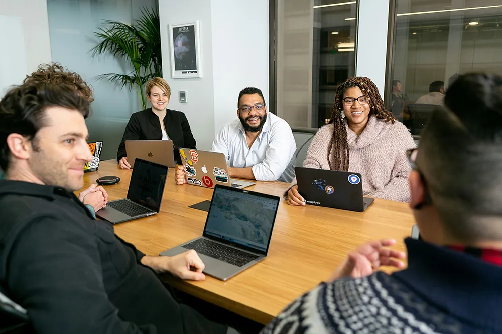 diverse resilient team meeting in a conference room with laptops