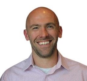 David Slobotski in a white and plum oxford shirt - smiling - white background